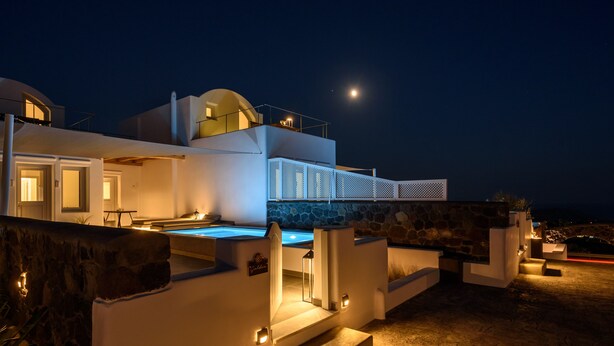 Une villa moderne dotée d’une piscine, de murs en pierre et offrant une vue sur le ciel nocturne illuminé par la lune.