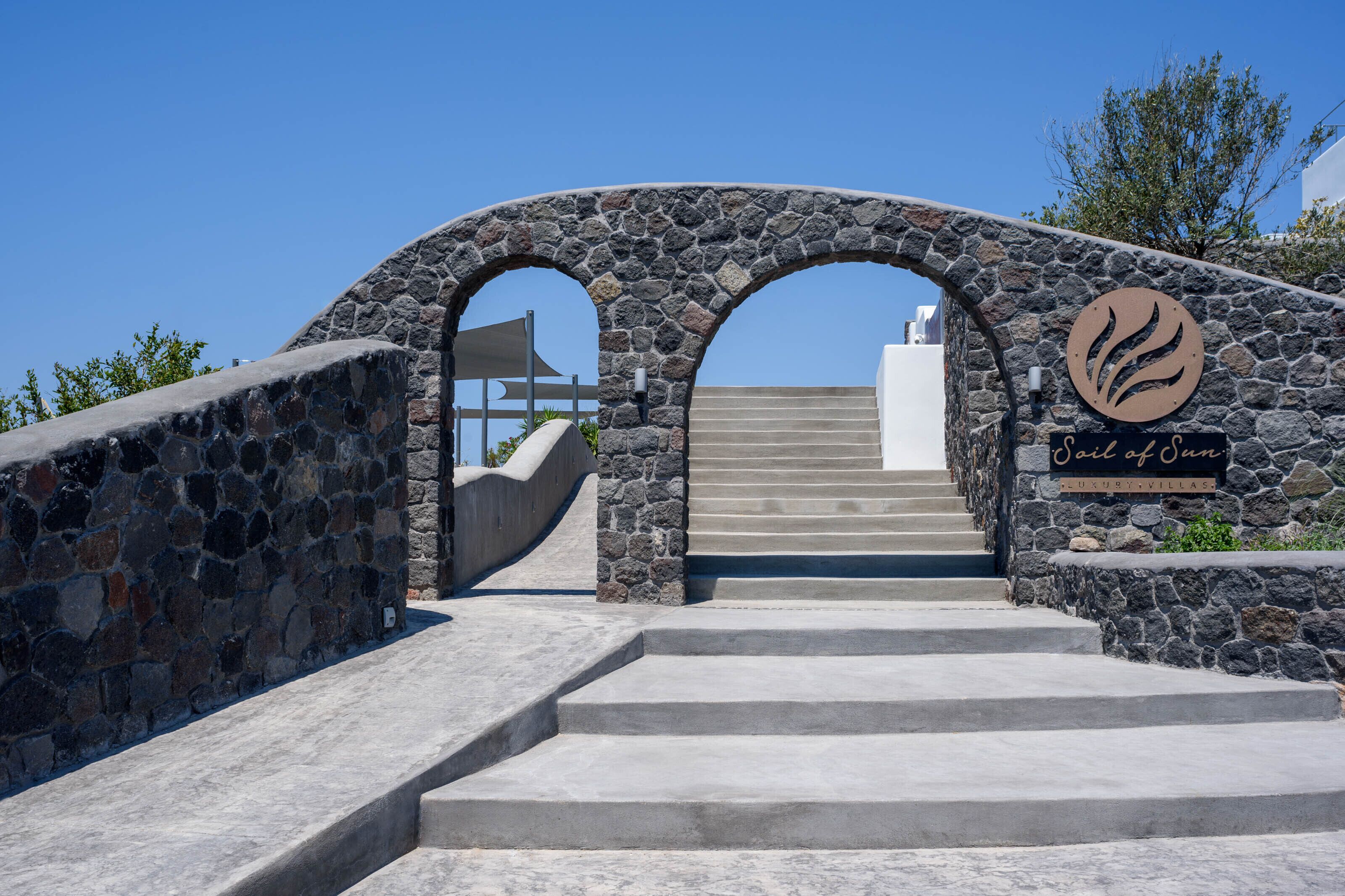 Un arco de piedra que conduce a una escalera con un letrero que dice "Sail of Our Luxury Villas".