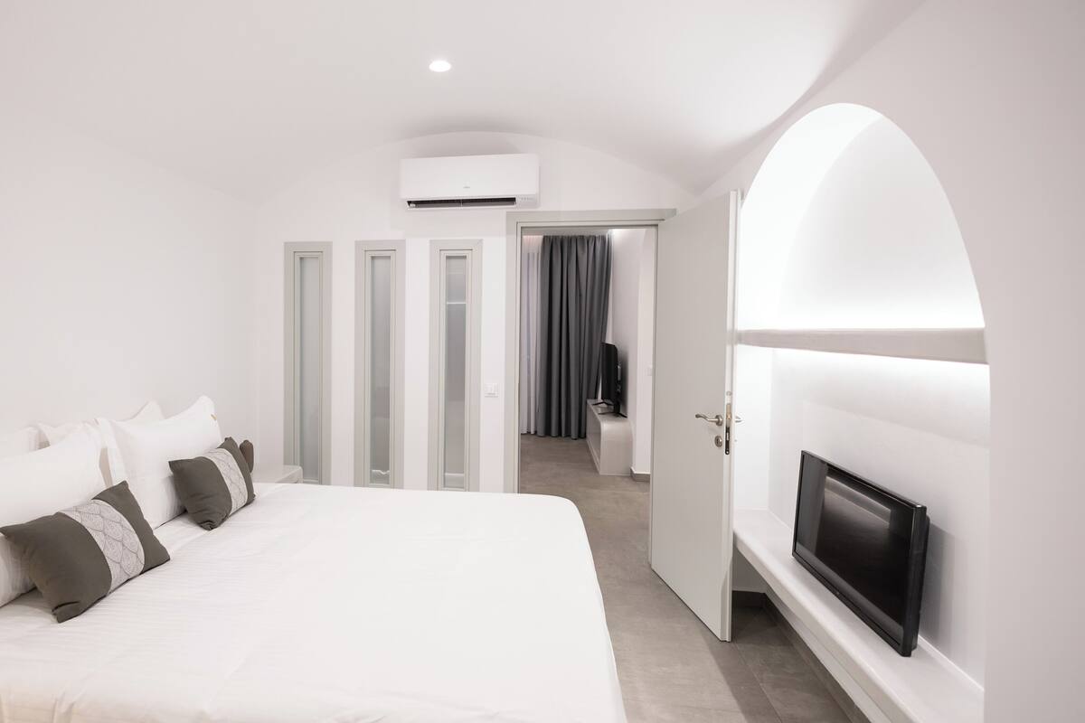 Une chambre d’hôtel moderne dotée d’un grand lit, d’un téléviseur à écran plat et d’un dressing.