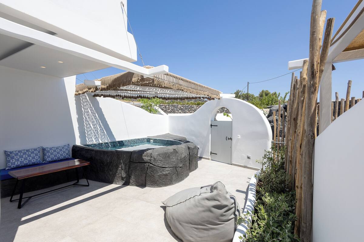 Un espace extérieur moderne doté d’un jacuzzi, d’un coin salon et d’une pergola en bois.