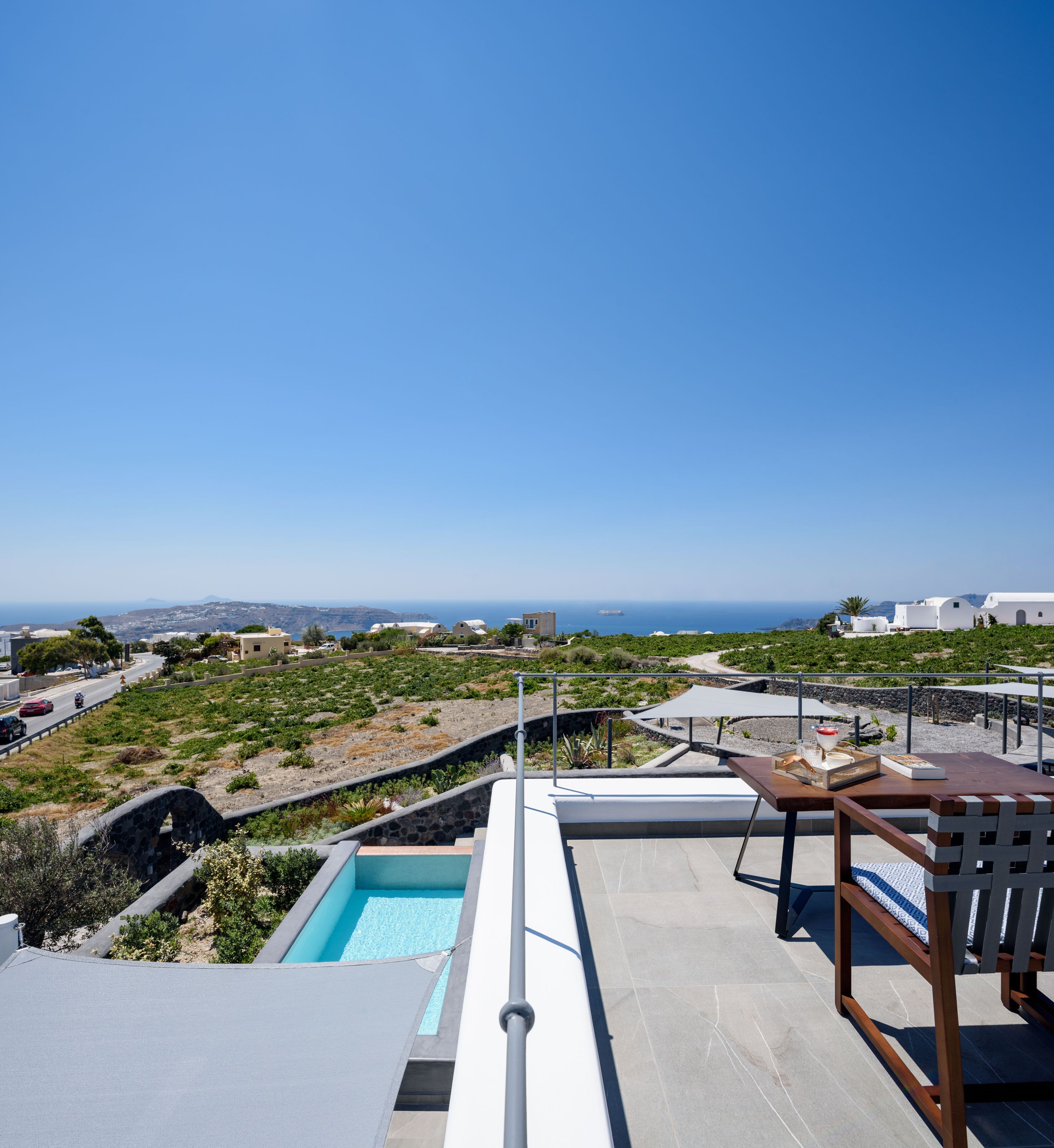 A rooftop terrace with a swimming pool, a dining area, and a view of the coastline.