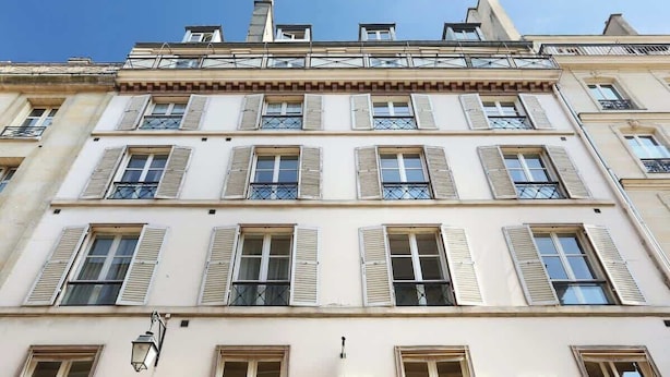 A multi-story building with a classic architectural style, featuring evenly spaced windows with shutters and balconies.