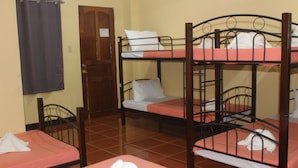Quarto com beliches, uma porta de madeira e uma cortina.