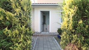 A house with a tiled entrance, a visible door, and a small garden area with a pathway. - Small vacation home with terrace - your oasis of relaxation 🏡🌞 near the Baltic Sea (Ortsamt 2)