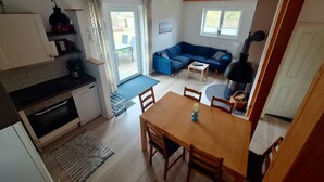 Un espacio habitable compacto con cocina, comedor y una zona de estar con sofá y chimenea.