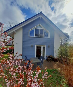 A two-story house with a front porch, a dining area with chairs, and a garage. - House for 6 people in Storkow - garden, fireplace, near the lake / center, quiet location (Storkow)