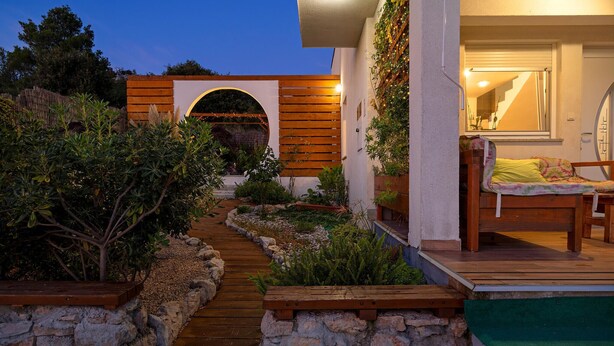 A garden pathway leading to a wooden deck with a bed and a chair. - Beautiful home in Bilice (Bilice)