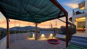 A rooftop terrace with a swing set, a trampoline, and a view of the cityscape at sunset. - Beautiful home in Bilice (Bilice)