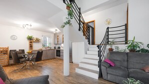 A modern living room with a staircase, a dining area, and a kitchen. - Beautiful home in Bilice (Bilice)