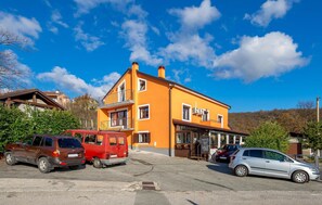Un immeuble de deux étages avec une façade jaune, un balcon et une enseigne indiquant « Hôtel ».