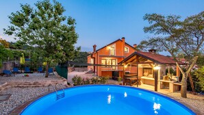 Ein zweistöckiges Haus mit Swimmingpool, Sitzgelegenheiten im Freien und einer Grillanlage.