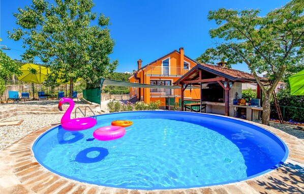 Une piscine avec des jeux gonflables, une terrasse en bois et un bâtiment à deux étages doté de balcons.