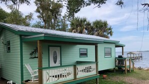 A small, single-story house with a green exterior and a porch. - Gorgeous Riverfront Fishing Cottage in Sebastian, FL - Summer 2026 Specials (Micco)