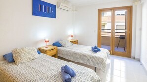 Hotellihuone, jossa on kaksi sänkyä, seinällä sininen taideteos ja liukuovi parvekkeelle.