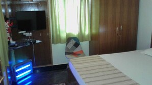 A bedroom with a bed, a TV, a desk with a computer, and a chair. - Maria's House  (Shiroda)