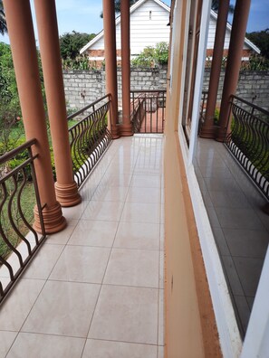 Un balcon abrité, doté d’un sol carrelé, de rampes en métal et de piliers en terre cuite.