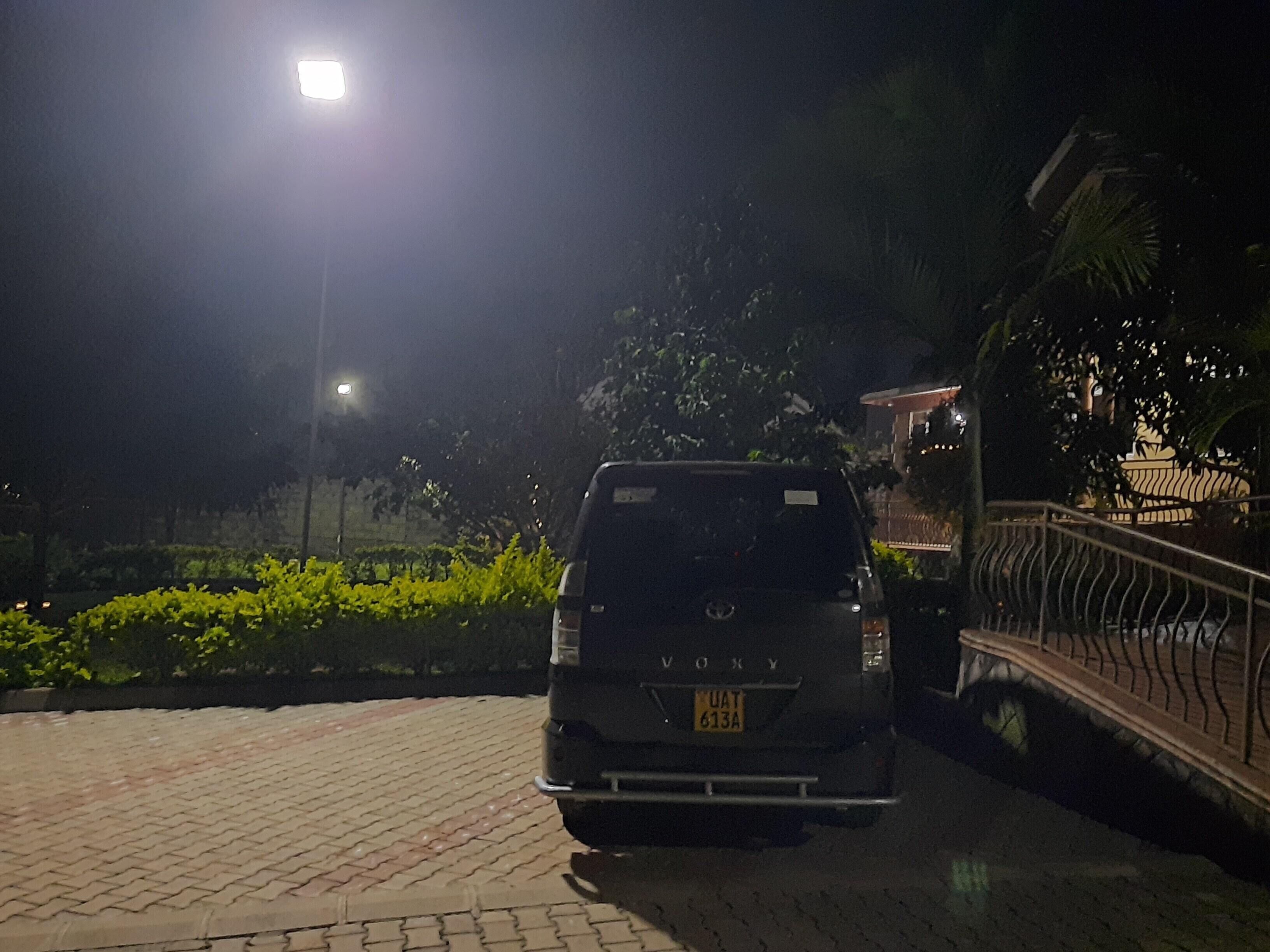 Un véhicule est garé sur une surface pavée, de nuit, avec un lampadaire en arrière-plan.