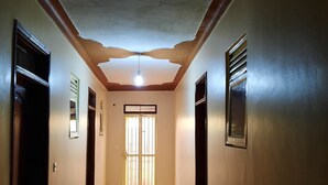 A hallway with a tiled floor, a ceiling with a light fixture, and a door with a window. - Airport Side Hotel Entebbe (Entebbe)