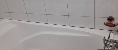 A white bathtub with a handheld showerhead and a red faucet.