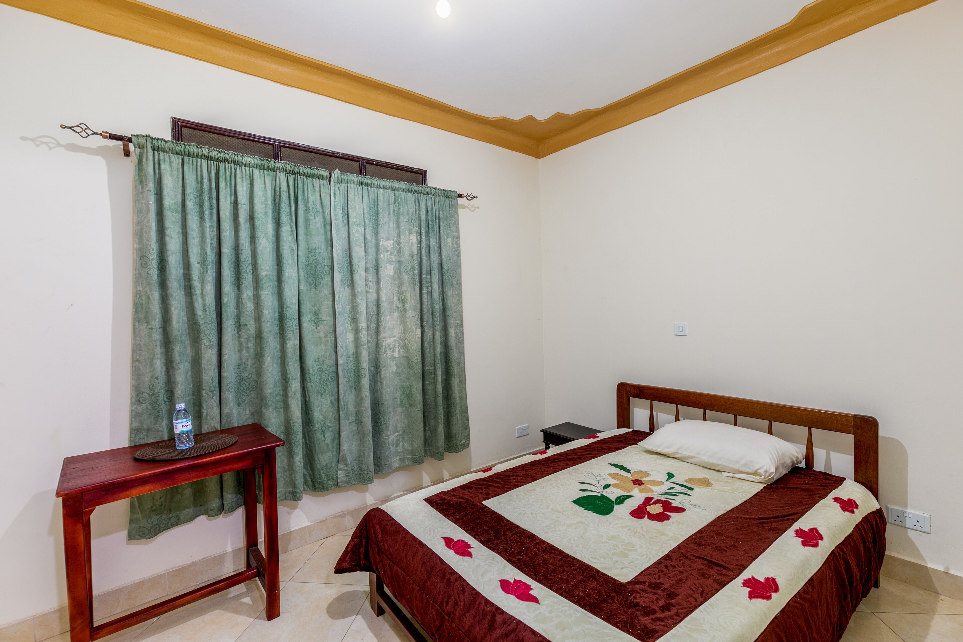 A bedroom with a bed, a bedside table, and a window with curtains.