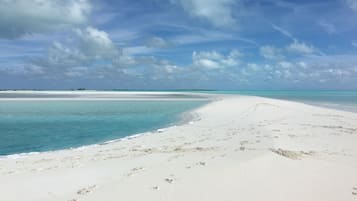 A wide sandy beach with clear turquoise waters and a distant horizon.