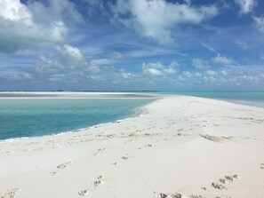 A wide sandy beach with clear turquoise waters and a distant horizon.