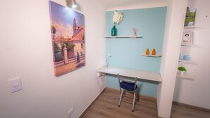 Quarto com escrivaninha, cadeira e um quadro na parede.