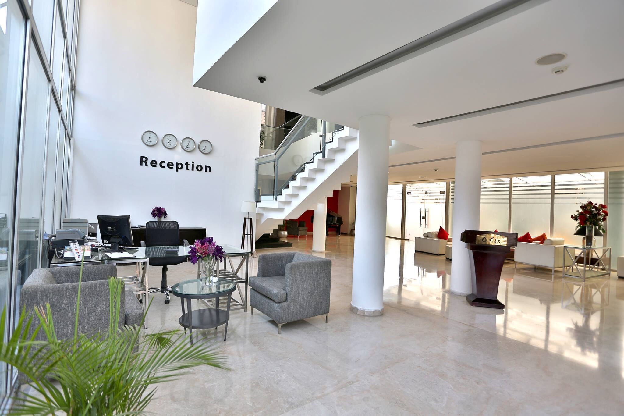 A modern reception area with a glass wall, a staircase, and a seating area with a glass table and chairs.