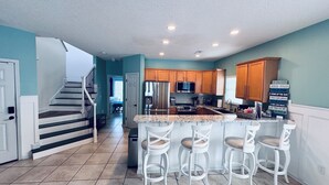 A modern kitchen with a central island, wooden cabinets, and a stainless steel refrigerator. - High Tide 5 Bedroom Ocean View House, Heated Pool, Hot Tub, Darts, King beds (Surfside Beach)
