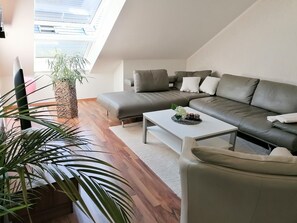 A modern living room with a sofa, a coffee table, and a potted plant.