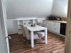 A compact kitchen with a white table, chairs, and a microwave.