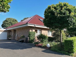A single-story house with a red-tiled roof, a brick facade, and a front garage.