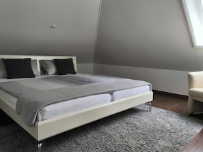 Une chambre Ă coucher avec un lit, une chaise et un sol recouvert de moquette.