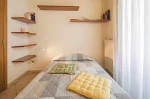 A bedroom with a bed, a radiator, and multiple wooden shelves on the wall.