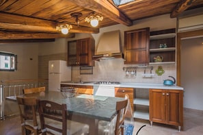 A kitchen with wooden cabinets, a marble countertop, and a dining area with a table and chairs.