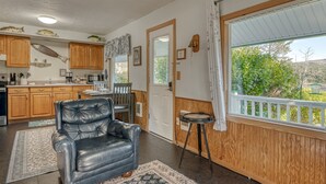 Una cocina con armarios de madera, una mesa de comedor, un sillón de cuero y vistas a través de una ventana.