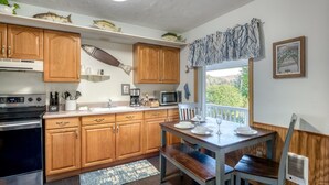 Una cocina con armarios de madera, microondas, estufa y una mesa de comedor con sillas.