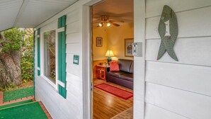 Un porche cubierto con un felpudo verde, una pared exterior blanca y una decoración con forma de pez.