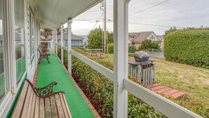 A covered porch with wooden benches, a green artificial turf, and a view of a residential neighborhood. - T05 - Dinghy @ Trollers Lodge (Depoe Bay)