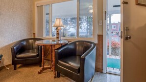 A room with two leather armchairs, a small wooden table, and a lamp. A large window provides a view of the outside. - T11 - Trawler @ Trollers Lodge (Depoe Bay)