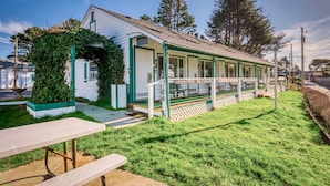 A small building with a covered porch, a picnic table, and a grassy area. - T09 - Lighthouse @ Trollers Lodge (Depoe Bay)