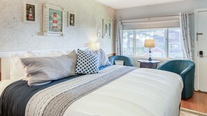 A hotel room with a bed, two chairs, a lamp, and framed pictures on the wall. - T09 - Lighthouse @ Trollers Lodge (Depoe Bay)