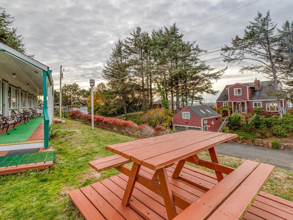 A picnic table in a grassy area with a building in the background.