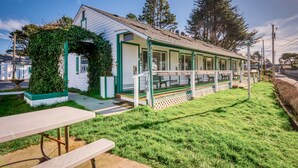 A small building with a covered porch, a picnic table, and a grassy area. - T10 - Skiff @ Trollers Lodge (Depoe Bay)