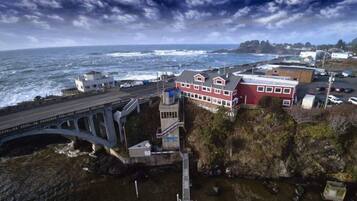 A coastal town with a prominent red building, a bridge, and a rocky shoreline.