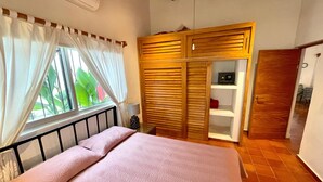 A bedroom with a bed, a window with curtains, a wardrobe, and a door. - Private home one block to the beach! 2 bedrooms. Premier Zona Dorado location! (Bucerias)