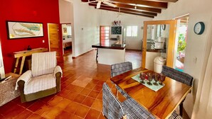A spacious living area with a dining table, chairs, a ceiling fan, and a kitchen in the background. - Private home one block to the beach! 2 bedrooms. Premier Zona Dorado location! (Bucerias)