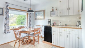 A kitchen with a dining table, chairs, a refrigerator, and cabinets. - T02 - Beacon @ Trollers Lodge (Depoe Bay)