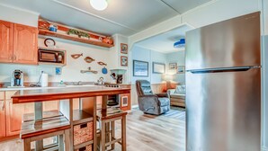 Cocina moderna con armarios de madera, refrigerador de acero inoxidable y una barra con taburetes.
