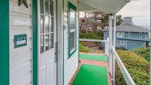 A house with a porch, a green door, and a number 6 sign on the wall. - T06 - Dory @ Trollers Lodge (Depoe Bay)
